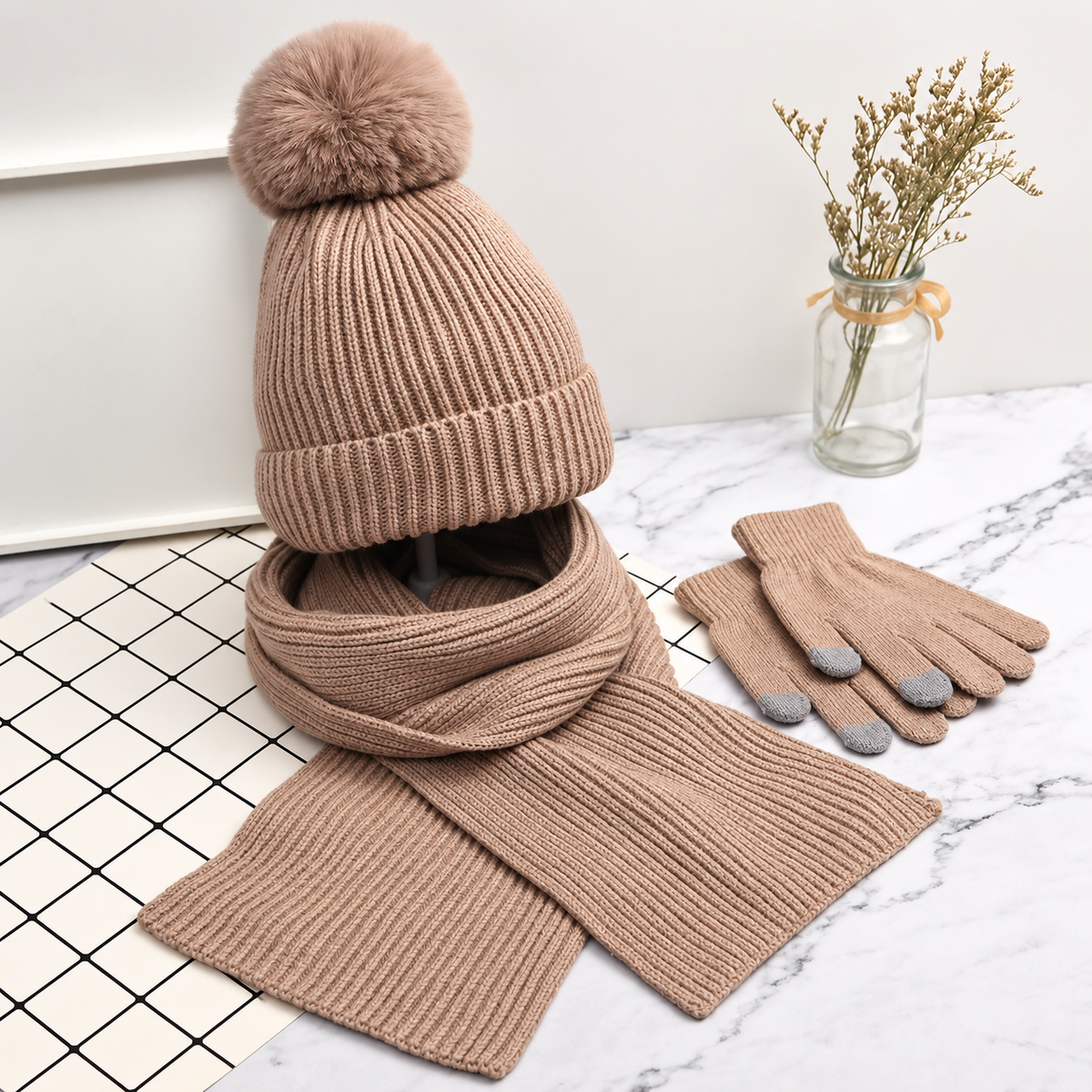 Beige knit pom-pom hat, scarf and gloves displayed together