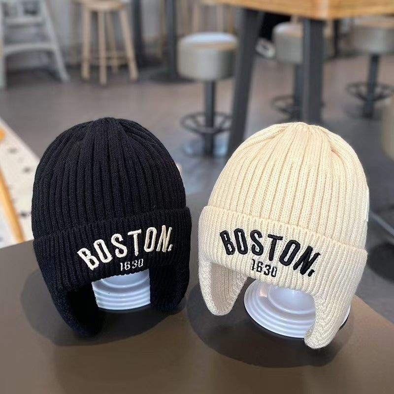 Black and cream white ear-flap beanies displayed side by side