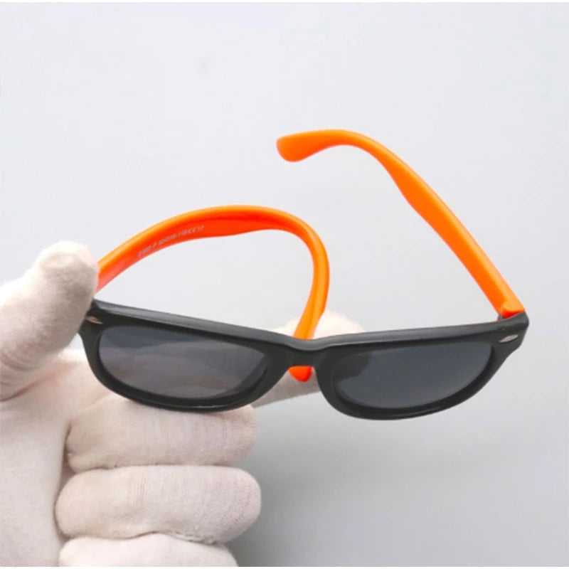 Black kids sunglasses with orange flexible arms bent outward