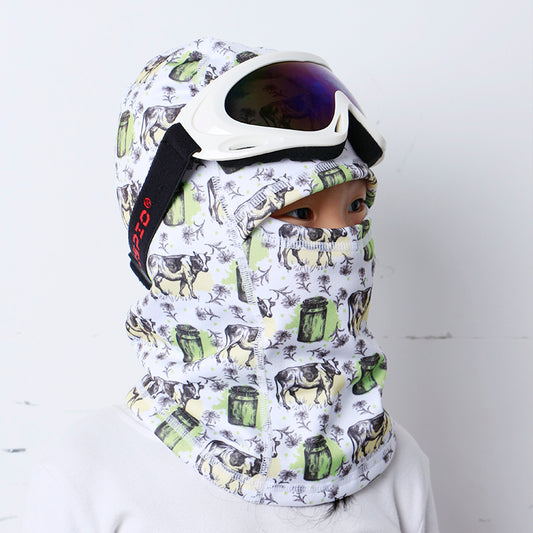 Child wearing a white and green printed balaclava with ski goggles