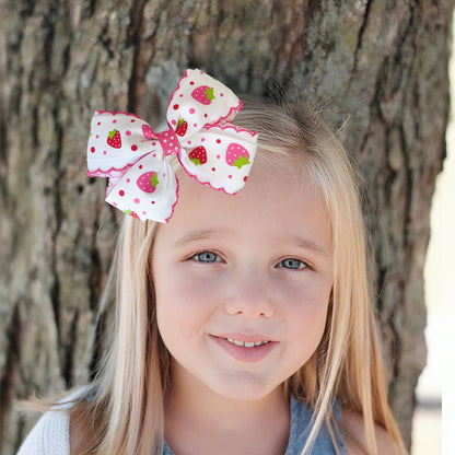 Child wearing a white and pink printed bow hair clip