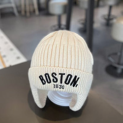 Cream white ribbed ear-flap beanie on a display head