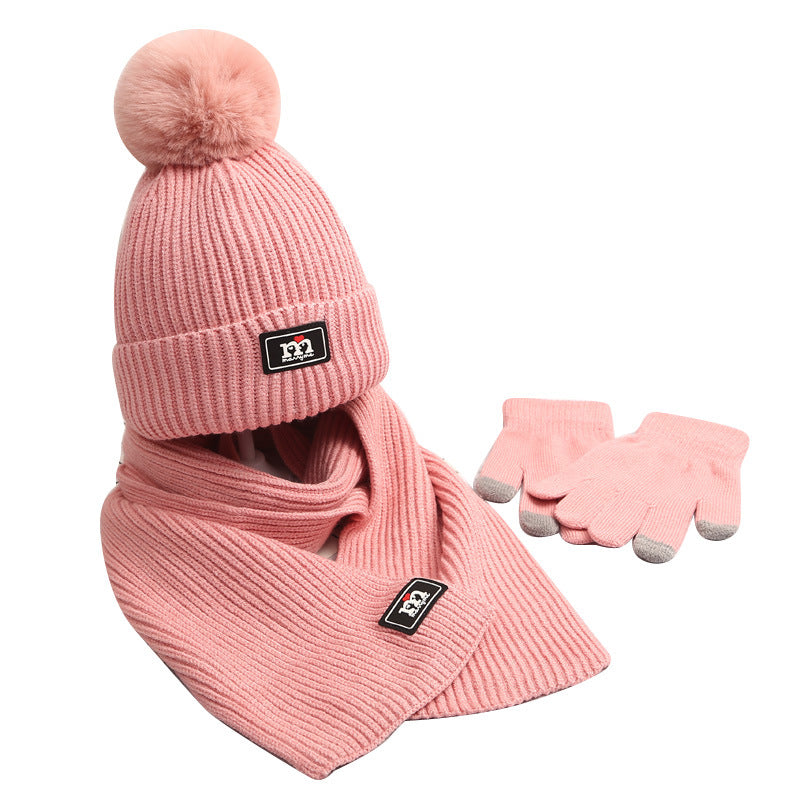 Pink knit pom-pom hat, scarf and gloves displayed together
