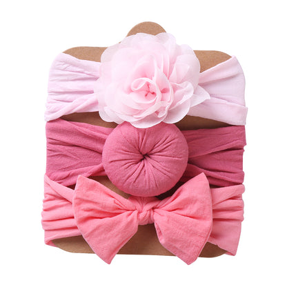 Three pink baby headbands with flower, round knot and bow decorations