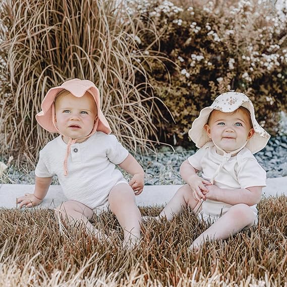 Two children wearing cream sun hats outdoors