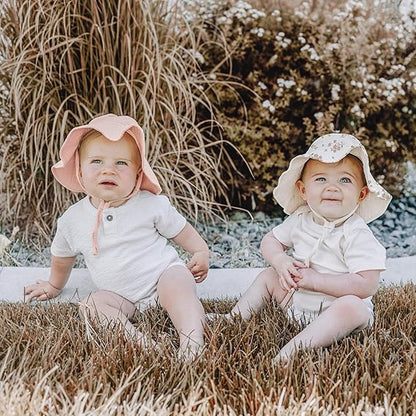 Two children wearing cream sun hats outdoors